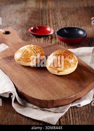 Petits pains appelés poğaça sur une planche en bois rustique avec des bols Banque D'Images