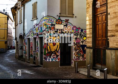 Une fresque de rue vibrante représentant un grand hibou jaune et des personnages fantaisistes décore le coin d'un bâtiment italien en pierre Banque D'Images