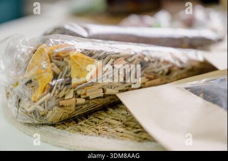 Une sélection de thé en feuilles en vrac et d'agrumes séchés dans un emballage individuel. Mélanges de tisanes et de thé aux fruits dans des emballages en papier et en plastique sur un t blanc Banque D'Images