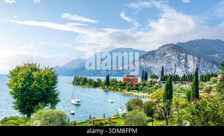 Vue panoramique sur les voiliers ancrés dans la baie du Val di Sogno près de Malcesine. Jardins et montagnes alpines surplombant le lac de Garde, Vénétie, Italie Banque D'Images