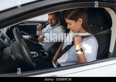 Port de la ceinture de sécurité. Femme est avec instructeur en voiture, concept d'école de conduite. Banque D'Images