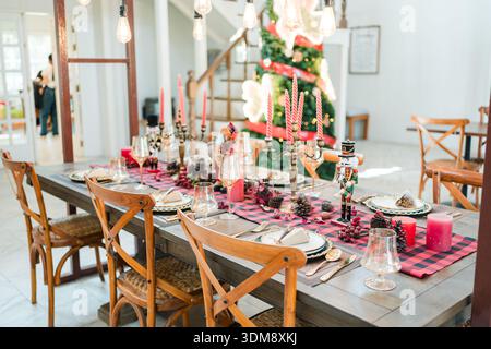 Élégante table de noël avec bougies rouges, ornements saisonniers et vaisselle classique pour dîner à la maison Banque D'Images