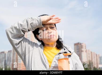 Sport et fitness. Sport senior. Les aînés actifs. Femme senior essuyant la transpiration après un entraînement dur en plein air dans le parc || modèle libéré Banque D'Images
