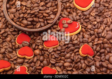 Fond de grains de café avec des biscuits en forme de coeur rouge et bol en bois Banque D'Images