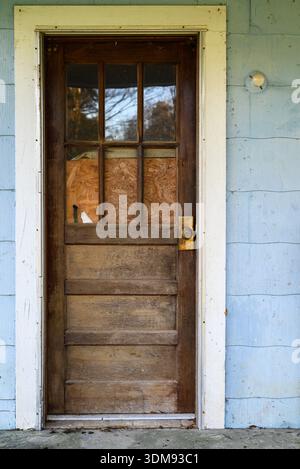 Mississippi, États-Unis – 20 janvier 2026 : une porte en bois altérée avec des panneaux de verre sur une vieille maison rurale, montrant des signes d'âge et d'abandon. Banque D'Images