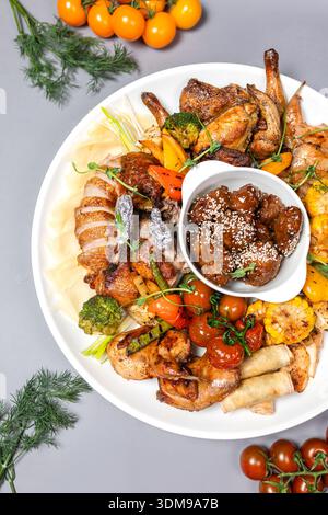 Vue de dessus du plateau de poulet avec des légumes et de la sauce sur une assiette blanche Banque D'Images