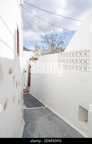 Ruelle blanche étroite à Emporio (Emborio ou Nimborios), Santorin, Grèce. Vue sur un clocher traditionnel des Cyclades à travers les murs blanchis à la chaux. Banque D'Images