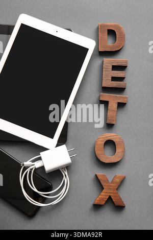 Mot DETOX fait de lettres en bois et de gadgets modernes sur fond gris Banque D'Images