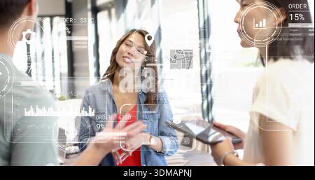Écoute femme coréenne en veste denim haut rouge gestuelle au bureau avec des superpositions HUD de tablette de téléphone Banque D'Images