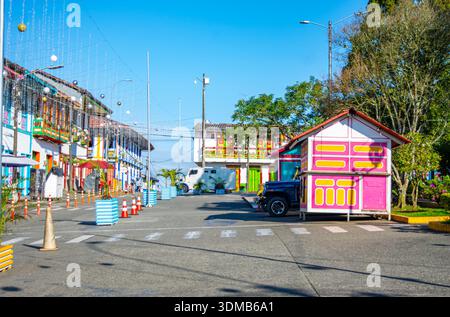 Une rue animée à Filandia avec des maisons magnifiquement peintes et une voiture noire classique garée par une journée ensoleillée. Banque D'Images