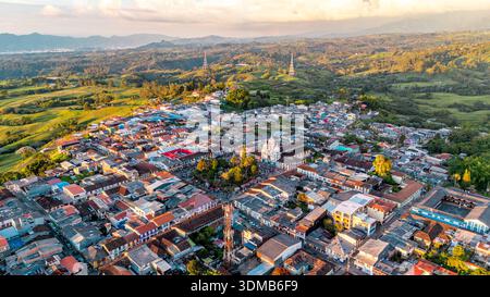 Les toits vibrants contrastent avec les collines verdoyantes de Filandia, en Colombie, illuminés par la douce lumière du soir. Banque D'Images