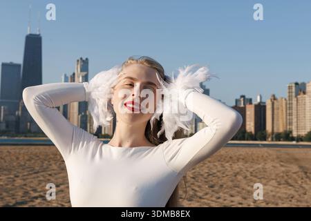 Femme blonde caucasienne mince souriante mature sur une plage en face de Chicago Landmark vue horizon Banque D'Images