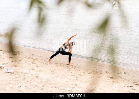 Femme en forme faisant de l'exercice de yoga par la rivière en saison d'automne. Banque D'Images