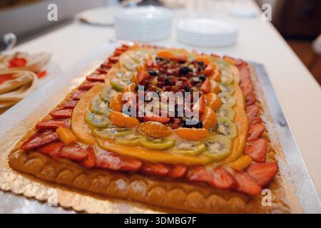 Une tarte rectangulaire joliment décorée débordant de fruits frais et vibrants et d'un glaçage étincelant, parfaite pour les fêtes Banque D'Images