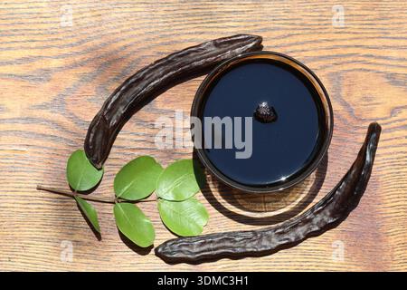 Mélasse de caroube et caroube sur fond en bois Banque D'Images