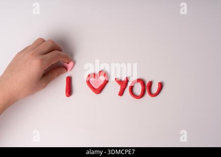 Une image douce et ludique avec la phrase 'i ? ? VOUS avez créé avec des lettres d'argile rouge sur un fond blanc. Les lettres peintes à la main ont un imperf Banque D'Images