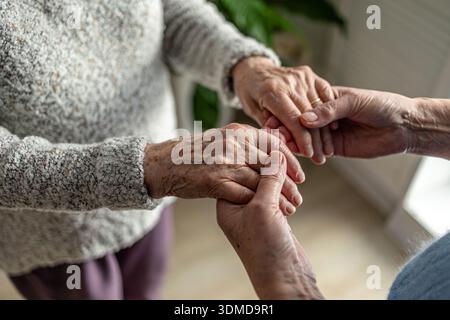 Femme âgée se tenant la main avec son soignant dans une maison de retraite, gros plan Banque D'Images