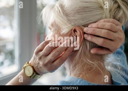 L'application de l'aide auditive Senior woman Banque D'Images