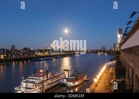 Angleterre, Londres, pleine lune sur Docklands et Canary Wharf Skyline la nuit Banque D'Images