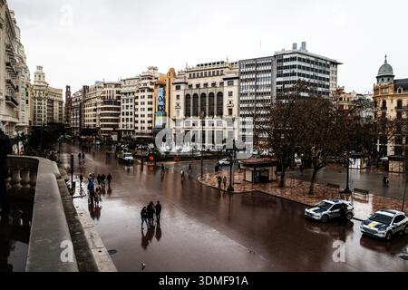 Vue surélevée sur une place de la ville baignée de pluie à Valence, en Espagne, avec une architecture historique, une fontaine et la vie urbaine de la rue. Banque D'Images