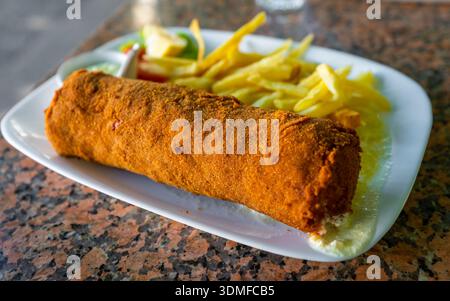 Schnitzel de Karadjordje pané avec des frites et une sauce crémeuse, dégusté pour le déjeuner à Trebinje, Bosnie-Herzégovine. Banque D'Images