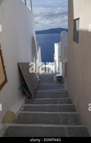 Escalier étroit en pierre à Fira, Santorin, Grèce. Entre l'architecture traditionnelle des Cyclades menant à la mer Égée bleue et la caldeira. Banque D'Images