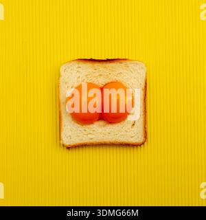 Oeuf fait de deux jaunes d'oeuf et morceau de pain grillé sur fond jaune. Pose à plat. Concept de Pâques. Banque D'Images