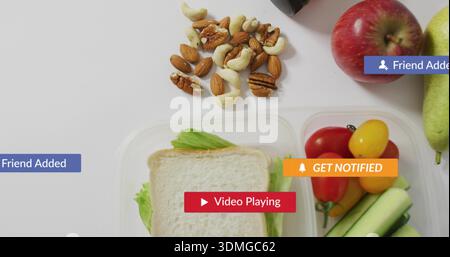 Affichage de boîte à lunch transparente en 3 parties avec sandwich, concombres, tomates sur une surface blanche, avec des badges Banque D'Images