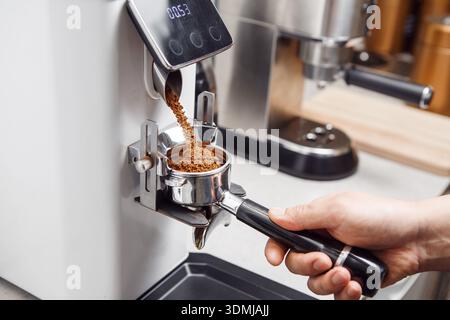 Café fraîchement moulu versé dans le porte-filtre du poste espresso Banque D'Images