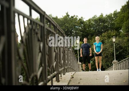Jeune couple debout sur un pont piétonnier avant de courir Banque D'Images