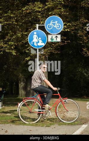 Jeune homme dans la vingtaine vélo sur la piste cyclable urbaine dans le parc vert Banque D'Images