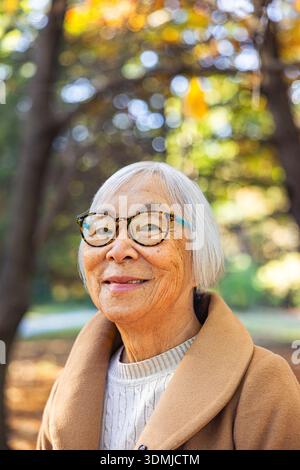 Femme asiatique senior souriante regardant la caméra dans un cadre naturel Banque D'Images