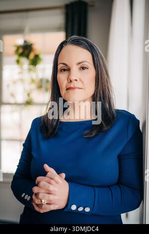 Femme mature confiante debout avec une expression sérieuse à l'intérieur Banque D'Images
