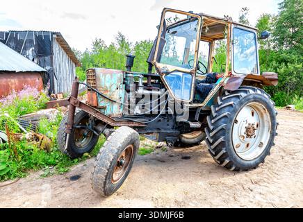 Novgorod, Russie - 26 juillet 2022 : vieux tracteur rouillé sur roues au village en été Banque D'Images
