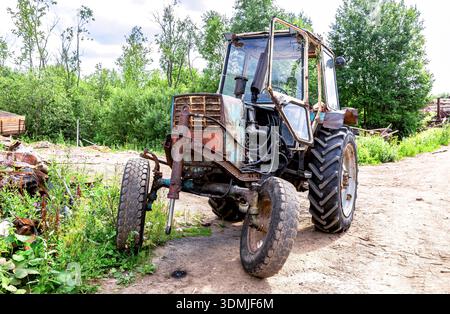 Novgorod, Russie - 26 juillet 2022 : vieux tracteur rouillé sur roues au village en été Banque D'Images