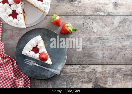 Tranche de gâteau aux fraises avec des fraises fraîches sur une table en bois Banque D'Images