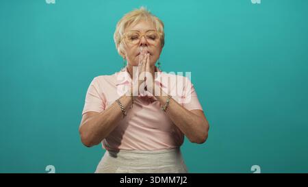 Femme âgée avec les mains pressées ensemble dans le geste de prière et les yeux fermés dans le studio toile de fond ; sérénité réflexion. Banque D'Images