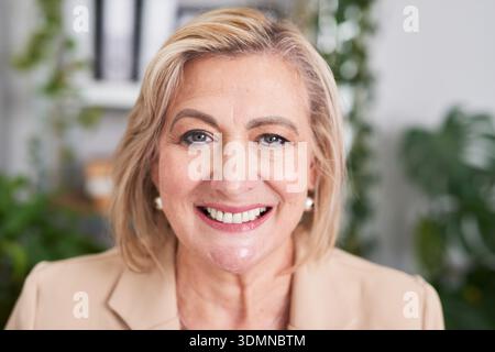 Femme d'affaires confiante avec cheveux blonds souriant dans l'environnement de bureau pour Portrait d'entreprise et Professional Headshot Banque D'Images