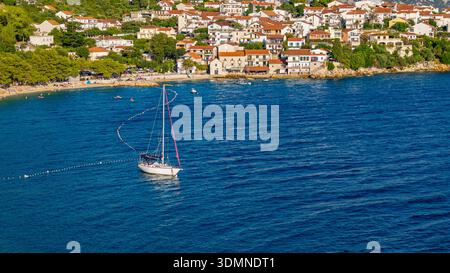 Voilier blanc sur les eaux calmes de l'Adriatique près de la ville côtière en Croatie vue aérienne de scène d'été Banque D'Images