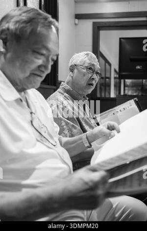 Les membres de la chorale de l'Église congrégationnelle de Waiokeola se préparent à servir à Honolulu, Hawaï. Le chœur, composé de chanteurs masculins, passe en revue la feuille mus Banque D'Images
