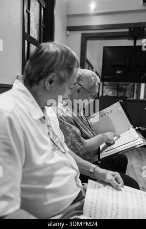 Les membres de la chorale masculine de l'Église congrégationale de Waiokeola examinent des partitions avant un service à Honolulu, Hawaï. Le chœur se prépare à leur perf Banque D'Images