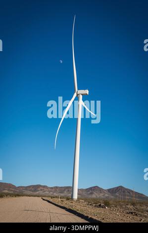 Un moulin à vent électrique géant avec la lune montrant à travers ses pales. Un parc éolien solaire entre Kingman AZ et Las Vegas Nevada. Banque D'Images