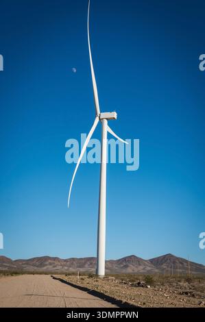 Un moulin à vent électrique géant avec la lune montrant à travers ses pales. Un parc éolien solaire entre Kingman AZ et Las Vegas Nevada. Banque D'Images