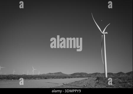 Un moulin à vent électrique géant avec la lune montrant à travers ses pales. Un parc éolien solaire entre Kingman AZ et Las Vegas Nevada. Noir a Banque D'Images
