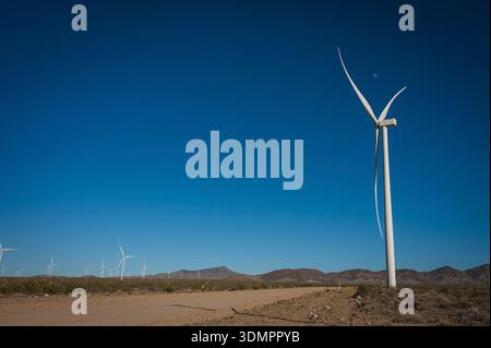 Un moulin à vent électrique géant avec la lune montrant à travers ses pales. Un parc éolien solaire entre Kingman AZ et Las Vegas Nevada. Banque D'Images