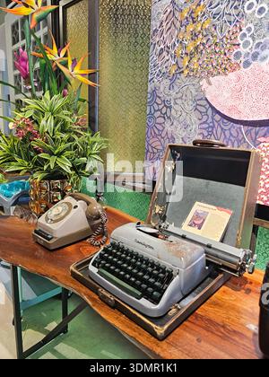 Vintage Remington machine à écrire et téléphone rotatif avec arrangement floral exotique. Banque D'Images