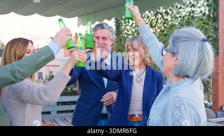 Amis toast avec des bouteilles profitant de la fête sur le toit Banque D'Images