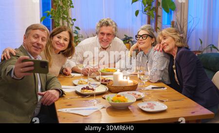 Amis souriants appréciant le dîner faisant un selfie Banque D'Images