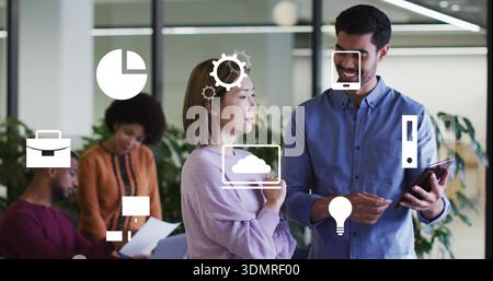 Homme en shirted bleu parlant et femme en sueur violette tenant tablette et papiers dans le bureau avec des icônes Banque D'Images