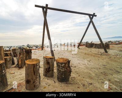 Structure de poteau en bois rustique et souches d'arbre sur Sandy Shoreline contre ciel couvert à Coastal Beach Area Banque D'Images
